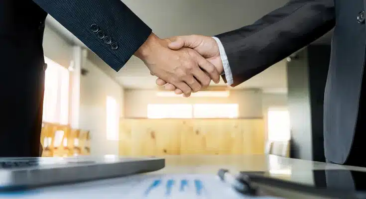 Dos empresarios cerrando un trato mientras se dan la mano