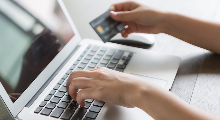 Persona sujetando su tarjeta de crédito mientras usa un portatil Profitline