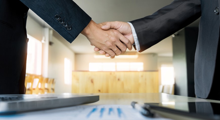 Dos empresarios cerrando un trato mientras se dan la mano Profitline
